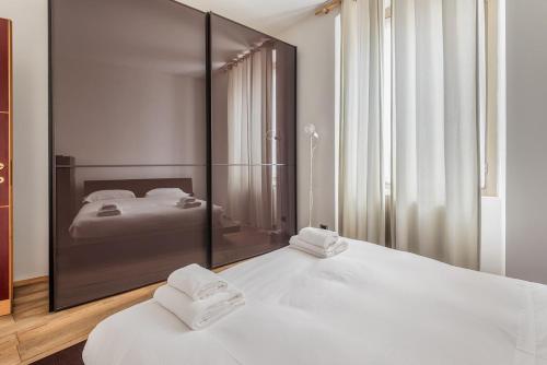 a bedroom with two white beds and a large mirror at Città alta Apartment-comfort in Bergamo