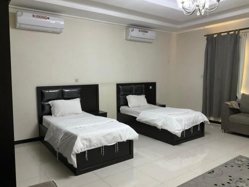 a bedroom with two beds and a couch at khaolha للشقق المخدومة in Al Hofuf