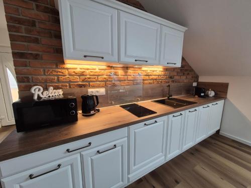 una cocina con armarios blancos y una pared de ladrillo en Apartmán By One, en Banská Štiavnica