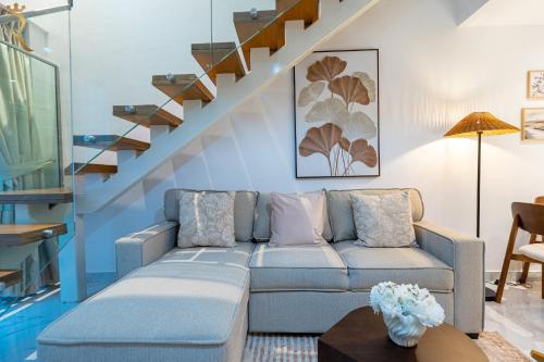 a living room with a couch and a staircase at 2BR Poolside Luxe - Chic Serene Escape in Abu Dhabi