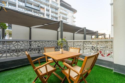 a table and chairs on a balcony with grass at 2BR Poolside Luxe - Chic Serene Escape in Abu Dhabi