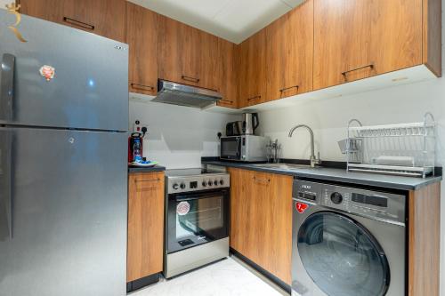 a kitchen with a washing machine and a washer at 2BR Poolside Luxe - Chic Serene Escape in Abu Dhabi