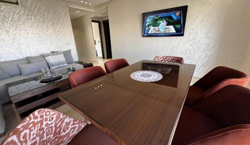 a living room with a wooden table and red chairs at Appart luxueux Marina Saïdia Tamaris 6 piscines in Saidia 
