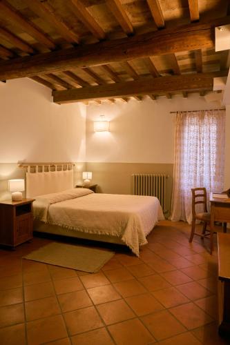 a bedroom with a bed and a table and a window at Residenza Antica Canonica in Città di Castello