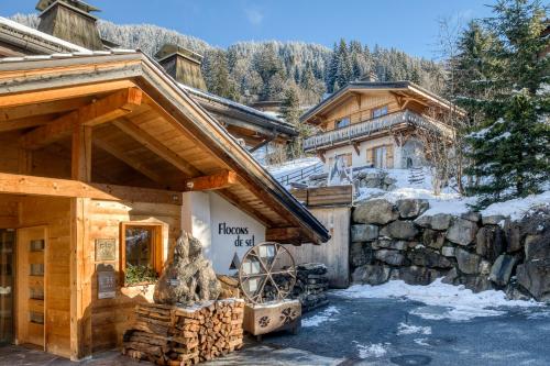 a log cabin in the snow with a windmill in front at Flocons de Sel - Relais & Chateaux in Megève