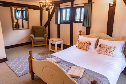 a bedroom with a large bed and a chair at 3 Bed Country House with Pool and Sauna in Tibenham