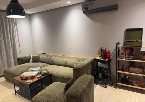 Una sala de estar con un sofá y un televisor en Studio Zenata Central Park Près de la plage Vue Piscine, en Aïn Harrouda