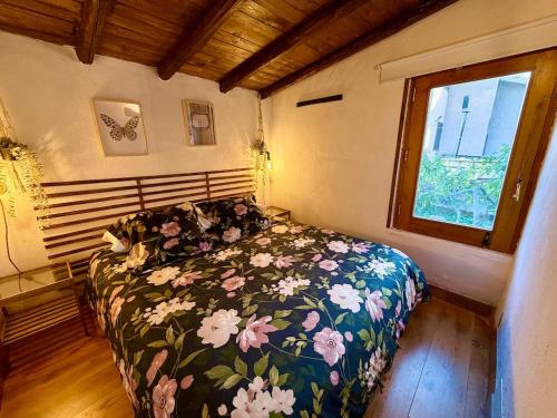 a bedroom with a bed with a floral comforter and a window at Casetta sull’Etna in Nicolosi