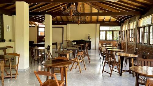 un restaurant avec des tables et des chaises en bois dans une salle dans l'établissement Pousada Sitio Sossego, à Petrópolis