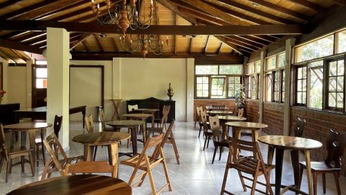 a room with wooden tables and chairs and windows at Pousada Sitio Sossego in Petrópolis
