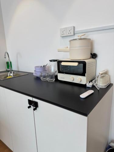 a kitchen counter with a toaster and a microwave at The Calm Corner in Kota Samarahan