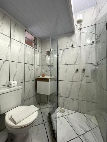 a bathroom with a toilet and a glass shower at Pousada Sitio Sossego in Petrópolis