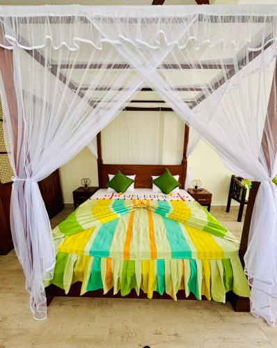a bedroom with a colorful bed with a canopy at Dinewa Apartment in Aluthgama