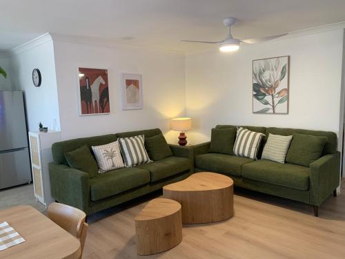 a living room with a green couch and a table at Fresh & fabulous 4 bedroom villa - walk to Curtin University in Perth