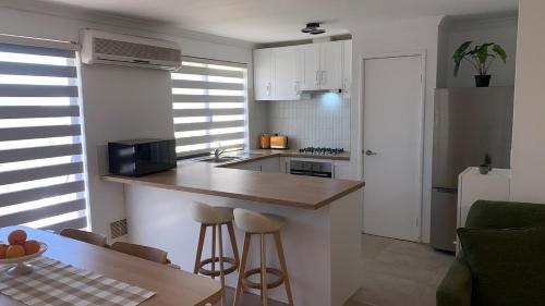 a kitchen with a counter and stools in a room at Fresh & fabulous 4 bedroom villa - walk to Curtin University in Perth