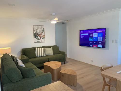 a living room with two green couches and a tv at Fresh & fabulous 4 bedroom villa - walk to Curtin University in Perth