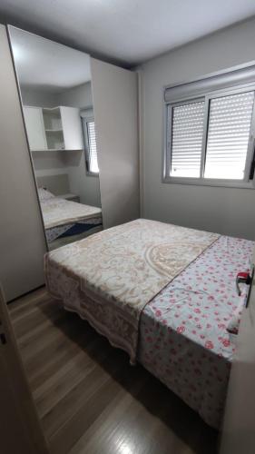 a small bedroom with a bed and a mirror at Apartamento completo e com ar-condicionado in Bento Gonçalves