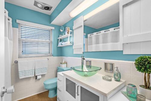 ein blaues Bad mit einem Waschbecken und einem WC in der Unterkunft Waterfront Bliss with Saltwater Pool, Hot Tub & Dockside Fire Table - Kathys Cottage - Roelens in Cape Coral