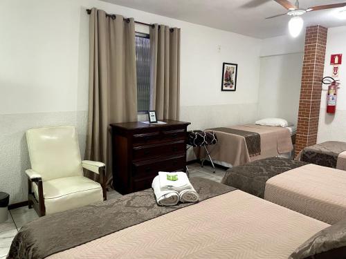 a hotel room with two beds and a chair at Pousada Sitio Sossego in Petrópolis