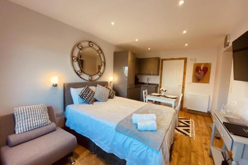 a bedroom with a bed and a chair and a mirror at Beautiful 1-Bed studio in Penrith in Penrith