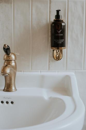 a bathroom sink with a soap dispenser and a bottle of soap at The Boars Head, Fife Restaurant and Rooms in Auchtermuchty