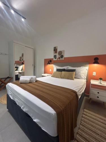 a bedroom with a large bed with an orange wall at Compact Home Campinas in Campinas