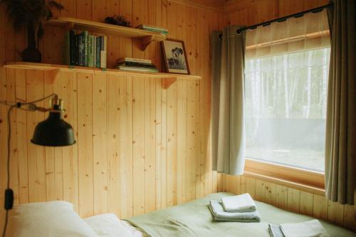 a bedroom with a bed and a window and a lamp at Miło las widzieć in Ciwoniuki