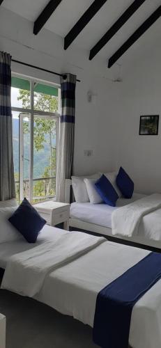 two beds in a room with a window at Florence Cottage in Beddegama