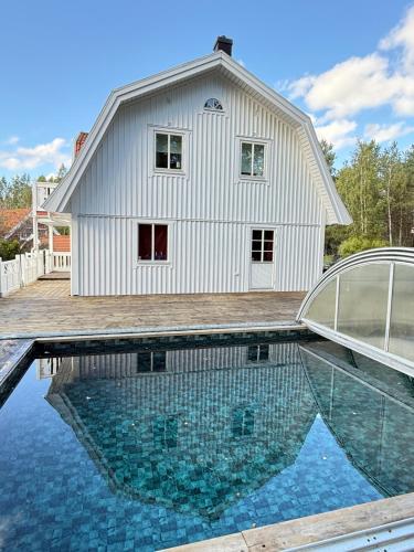 ein Haus mit einem Swimmingpool vor einem Gebäude in der Unterkunft Glamping in a Bungalow Deluxe by the Forest w Swimmingpool near Golf and the Baltic Sea Beach in Järna