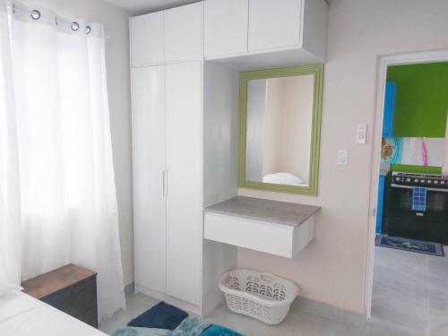 ブリッジタウンにあるGrateful 3bd B by ZenBreakの鏡と洗面台のある白い寝室