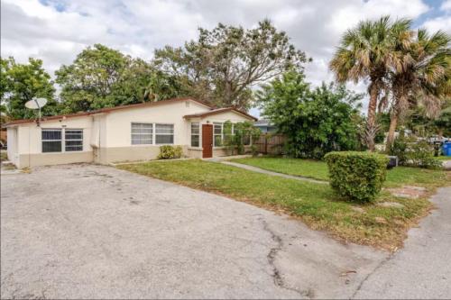 a house with a palm tree and a driveway at West Palm Beach Hideaway J2A in Lantana