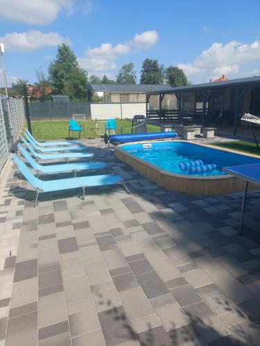a large swimming pool with blue chairs in a yard at Tin Men Apartmanház in Tiszafüred