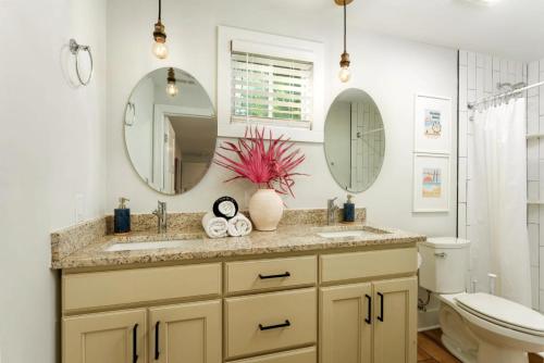 a bathroom with two sinks and a toilet and two mirrors at Downtown Retreat, 5BR Game Room & Pet Friendly in Wilmington