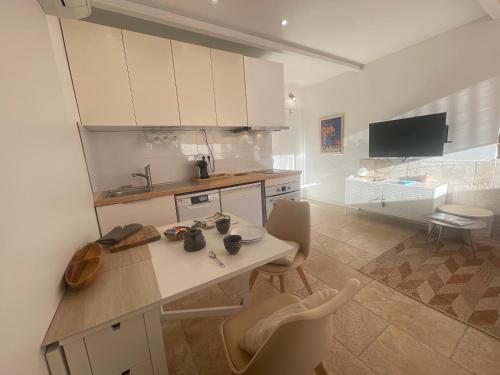 eine Küche mit weißen Schränken und einem Tisch und Stühlen in der Unterkunft Appart Bianca T2 - Terrasse - Parking - Calme - 1mn de la mer in Cassis