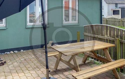 a wooden bench with an umbrella in front of a house at Lovely Home In Thyborøn With Wifi in Thyborøn
