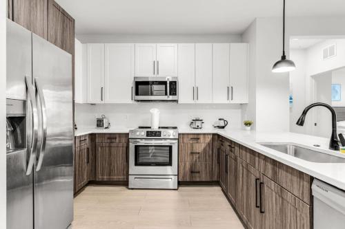 uma cozinha com armários de madeira e eletrodomésticos de aço inoxidável em Peaceful 2BR by the Bay Pool and Coastal Vibes em Apollo Beach