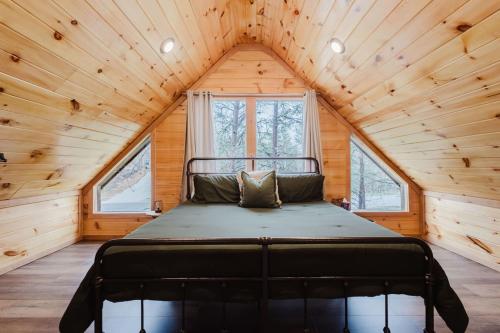 una cama en una habitación de una casa diminuta con techos de madera en Timber Pines at Red River Gorge, en Rogers