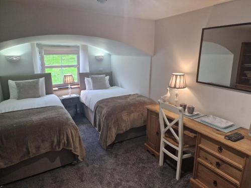 a room with two beds and a desk with a mirror at Teviotside Travel Inn in Hawick