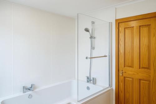 une salle de bain blanche avec une douche et un lavabo dans l'établissement 3 Bed Bungalow - Sleeps 6 - Pet Friendly - Parking, à Drummore