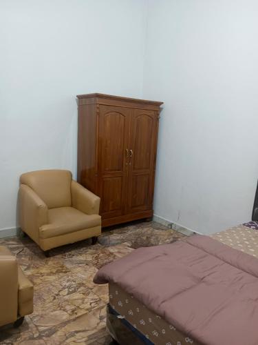 Un dormitorio con una cama, una silla y un armario. en Touchsmart, en Lemahabang