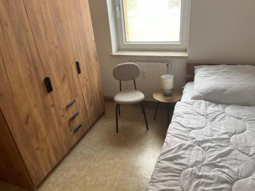 a bedroom with a bed and a chair and a window at Ferienwohnung P5 in Schmölln