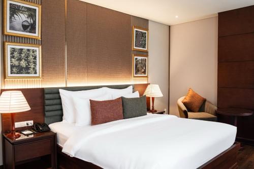 une chambre avec un grand lit blanc et une chaise dans l'établissement Kin Hotel Thi Sach, à Hô-Chi-Minh-Ville
