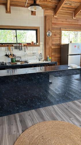 a kitchen with a black counter top and a refrigerator at cabañas refugio quillaileo in Santa Bárbara