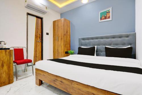 a bedroom with a large bed and a red chair at HOTEL O ANUSHTHAN in Jabalpur