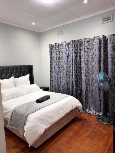 a bedroom with a bed with a black headboard and curtains at HavenTrust Guest house in Goodwood