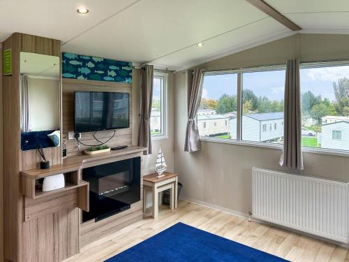een woonkamer met een tv en een groot raam bij Arran View Craig Tara in Ayr