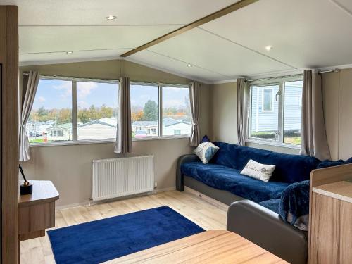 een woonkamer met een blauwe bank en ramen bij Arran View Craig Tara in Ayr