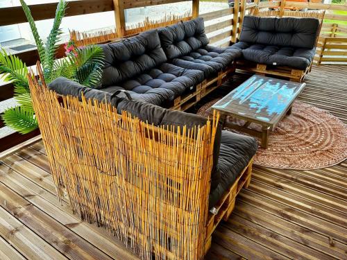 a couch and a table on a deck at Maison chic et paisible, terrasse, spa et campagne in Merceuil