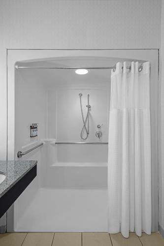 a white bathroom with a shower and a shower curtain at Hyatt Regency Pittsburgh International Airport in Clinton