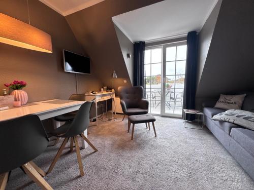 una habitación con un escritorio, sillas y un sofá en Maritim und individuell in Wenningstedt mit Balkon, en Wenningstedt